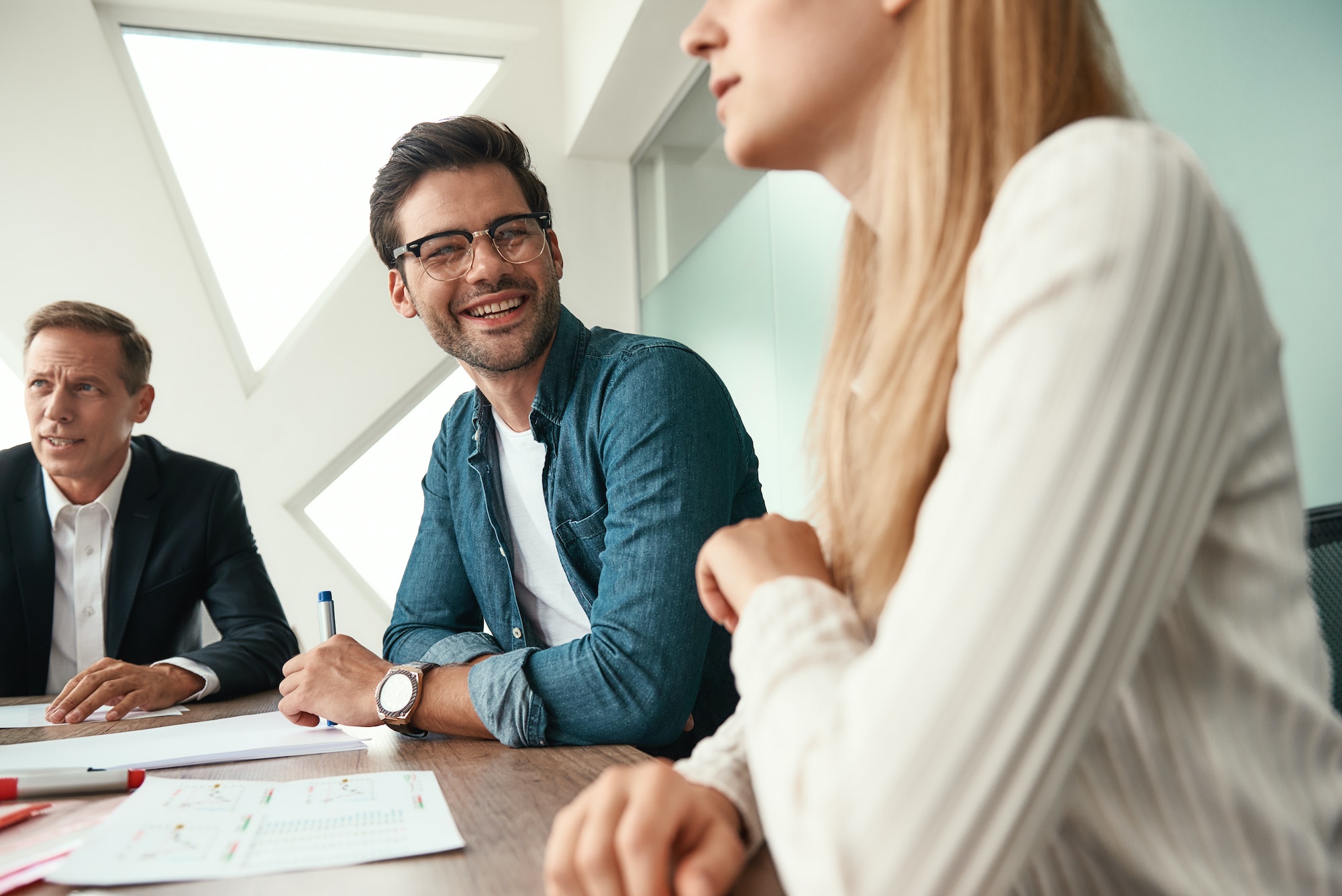 Morning meeting. Business team discussing something and smiling while sitting in the modern office